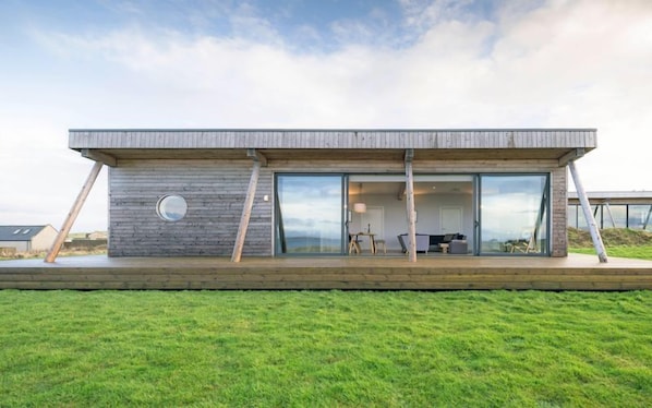 Une maison moderne avec un toit plat, de grandes fenêtres en verre et une terrasse en bois.