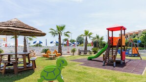 A playground with a slide, a climbing structure, and a turtle-shaped swing set. - Hotel Olympus (Caorle)