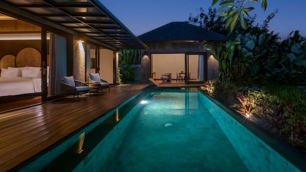 A swimming pool with a wooden deck, lounge chairs, and a covered seating area. - The Garcia Ubud Hotel & Resort (Ubud)