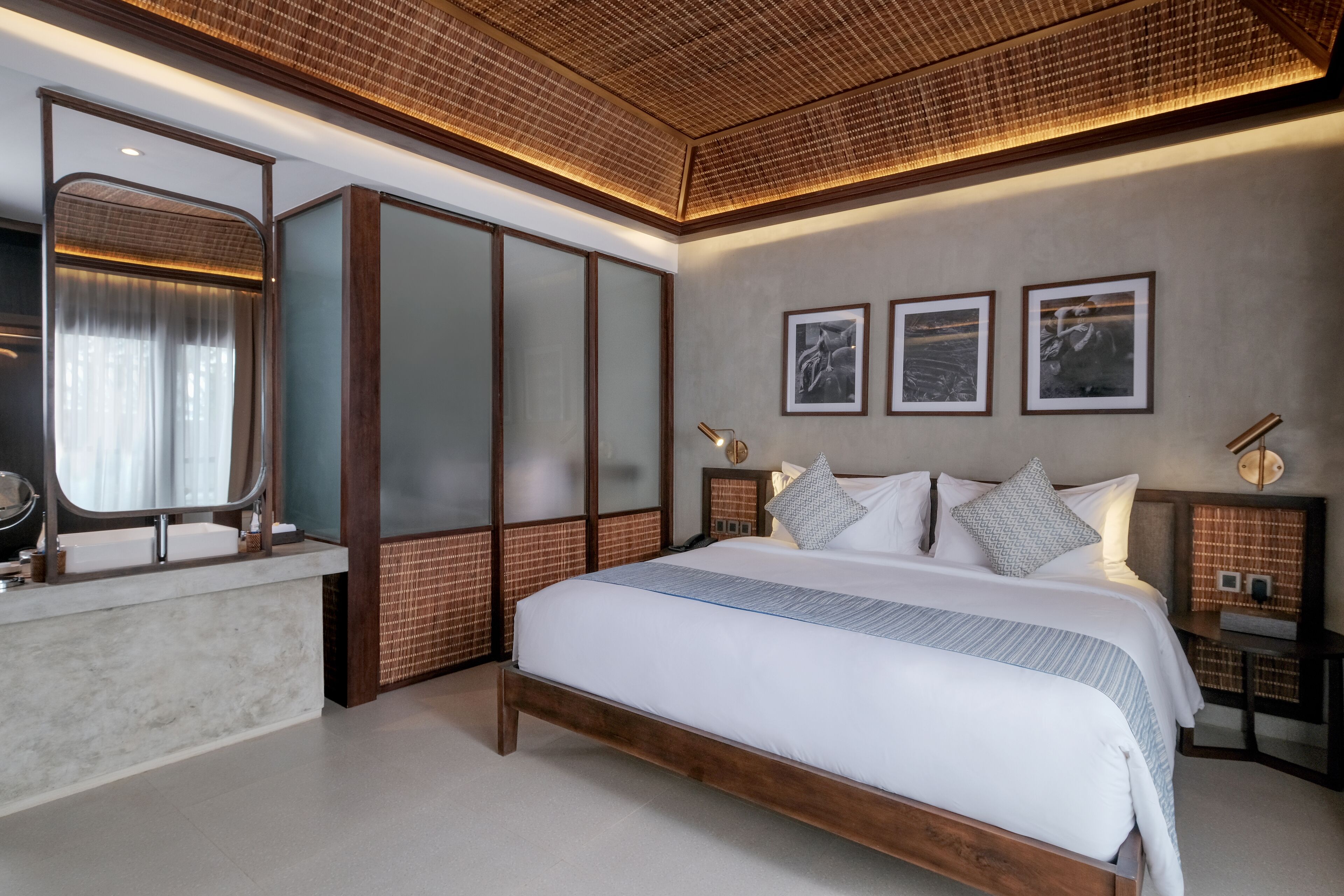 A modern bedroom with a large bed, a vanity with a mirror, and framed pictures on the wall.