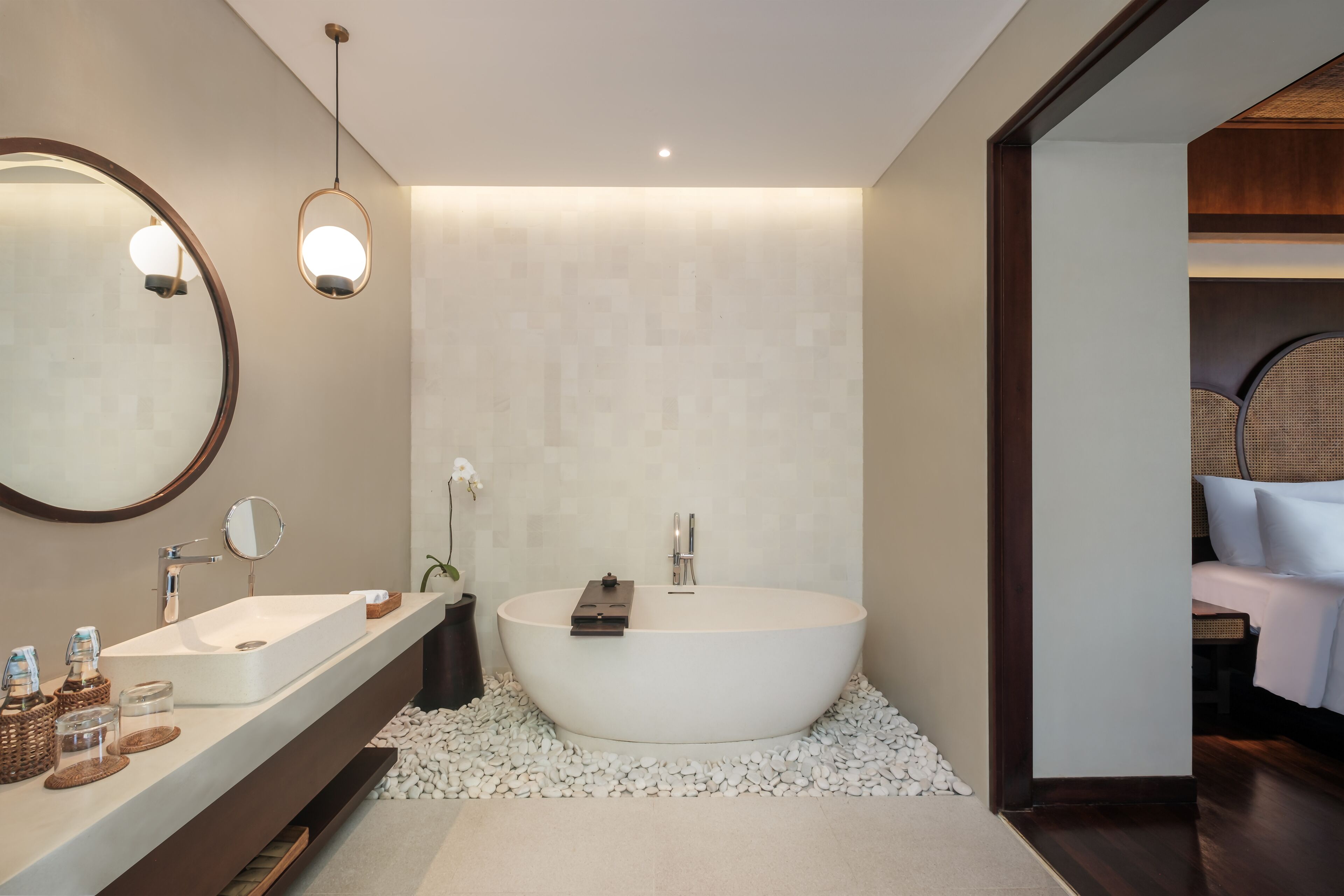 A modern bathroom with a freestanding bathtub, a large mirror, and a vanity with a sink and towel rack.