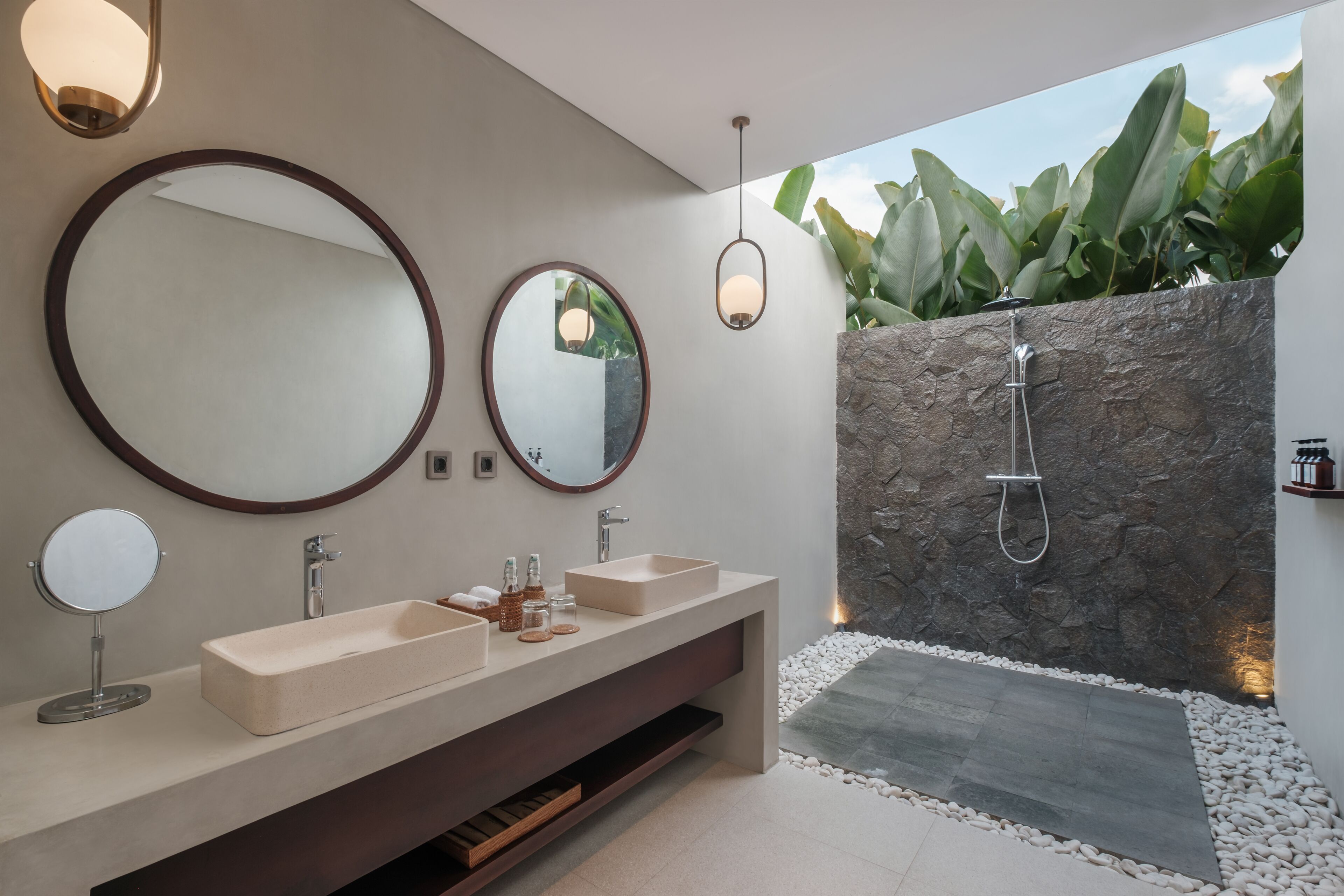 A modern bathroom with two sinks, a large mirror, and a shower.