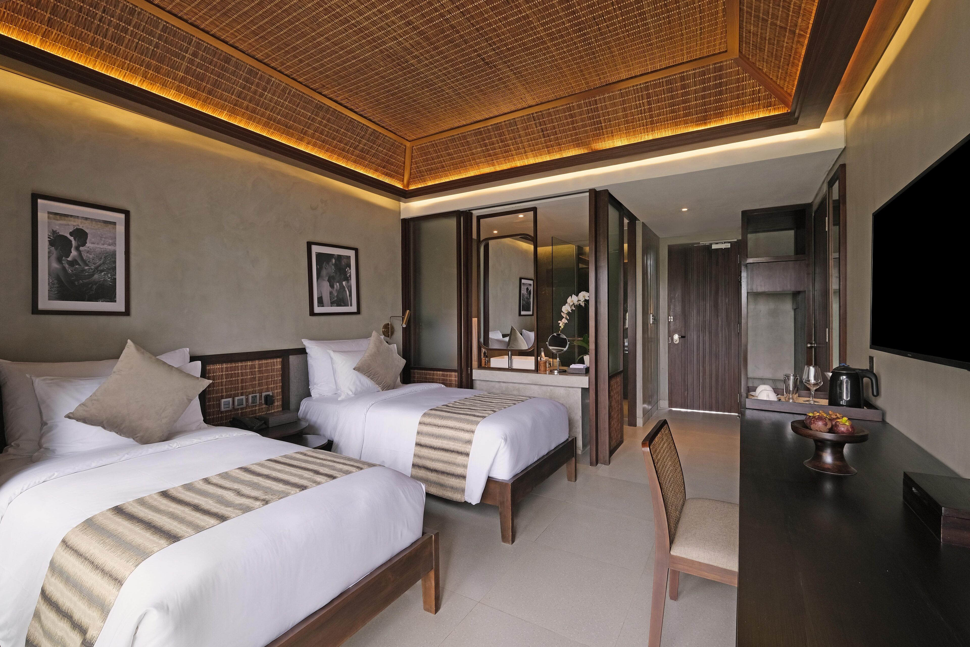 A hotel room with two beds, a desk, and a chair.