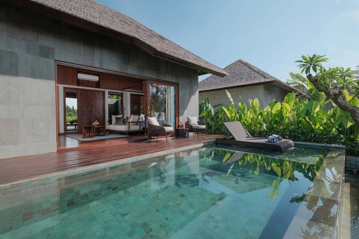 A modern villa with a swimming pool, wooden deck, and outdoor seating area.