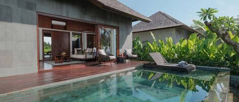 A modern villa with a swimming pool, wooden deck, and outdoor seating area.