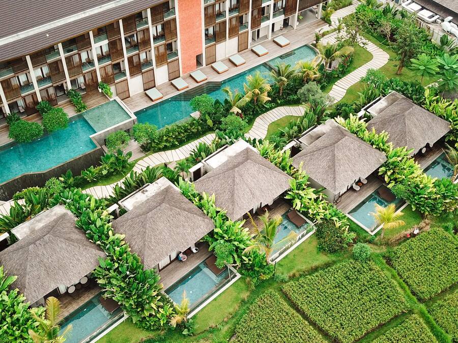 A resort with multiple swimming pools, thatched-roof cabanas, and lush greenery.