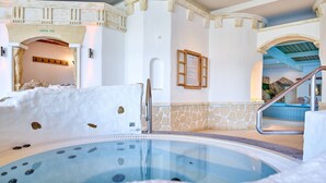 A hot tub area with a stone wall, a wooden archway, and a staircase leading to a balcony. - Parkhotel Bad Griesbach (Bad Griesbach im Rottal)