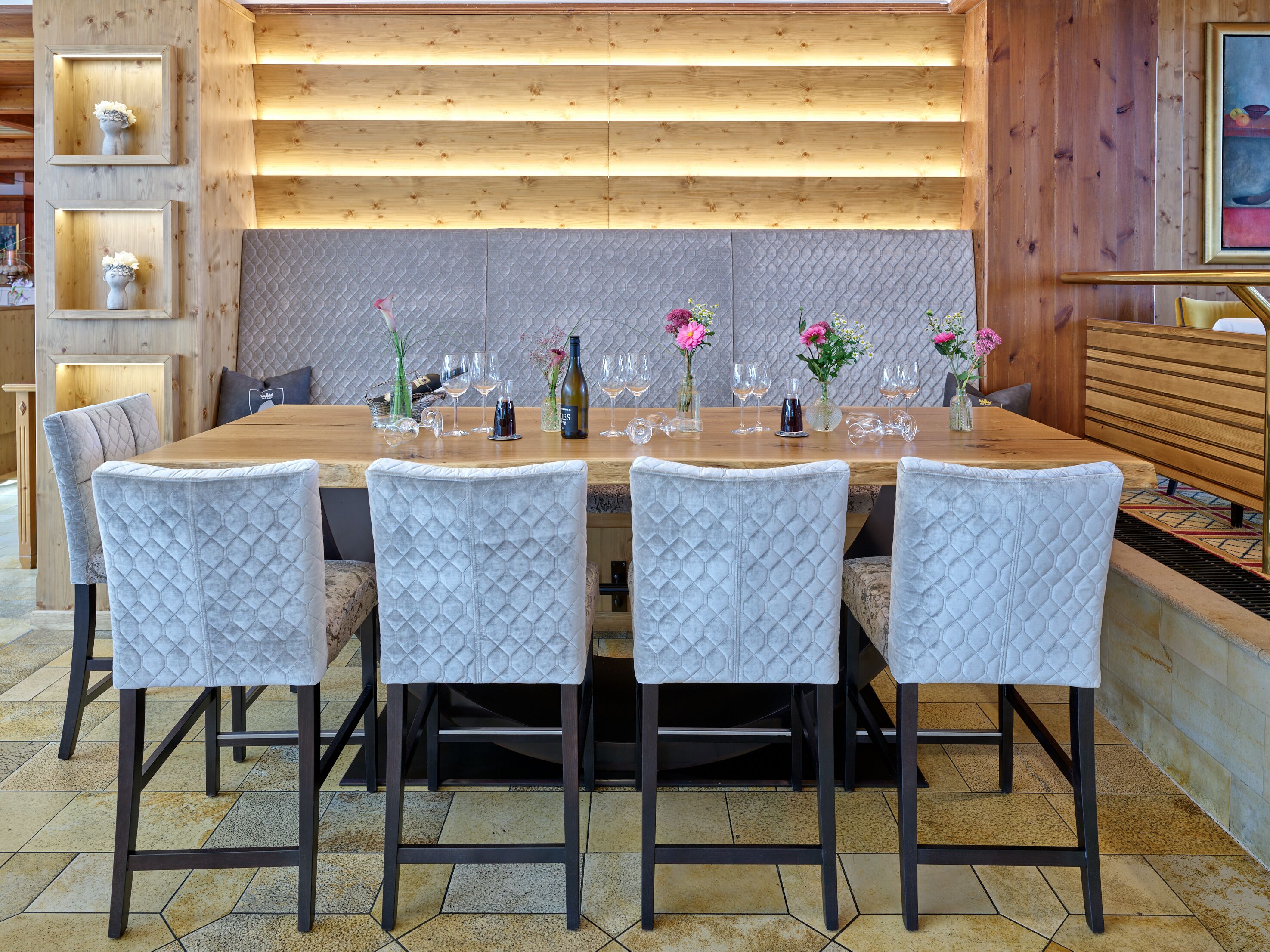 A dining area with a wooden table set for six, surrounded by cushioned chairs.