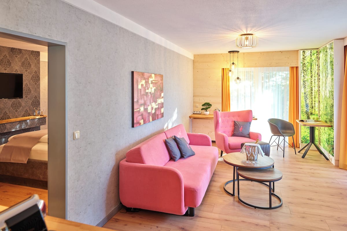 A modern living room with a pink sofa, a wooden coffee table, and a TV mounted on a textured wall.