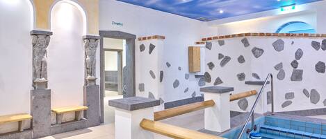 A spa area with a stone wall, a pool, and a wooden bench.