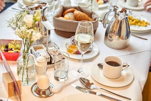 A breakfast setting with a variety of food items, a coffee pot, and a wine glass on a table. - Parkhotel Bad Griesbach (Bad Griesbach im Rottal)
