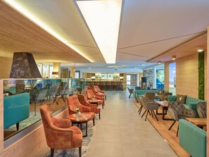 A modern hotel lobby with a bar area, seating arrangements, and a view of the outdoors. - Parkhotel Bad Griesbach (Bad Griesbach im Rottal)