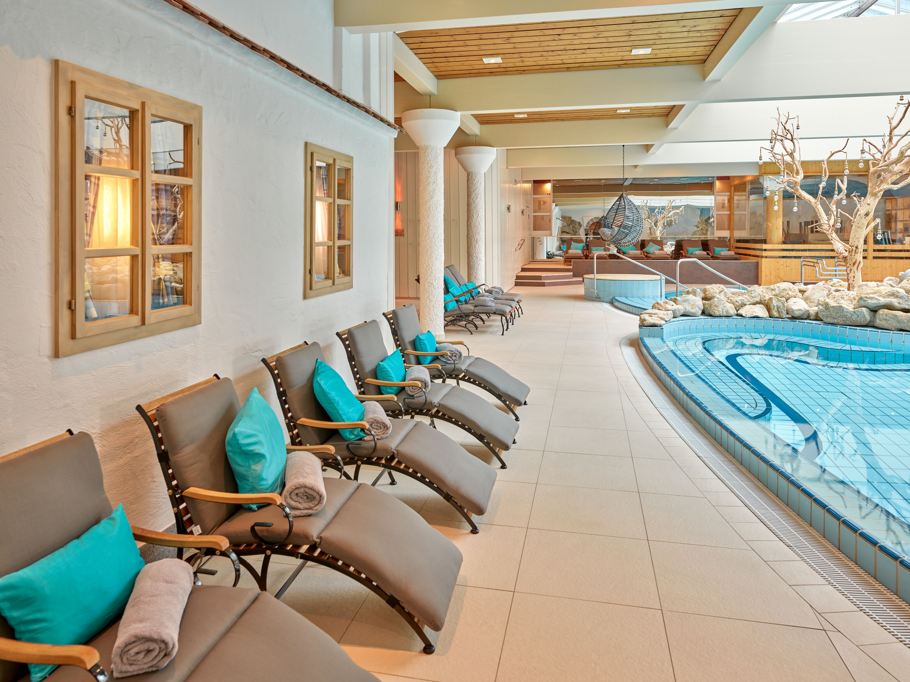 Un espace spa comprenant des chaises longues, une piscine et un plafond en bois.