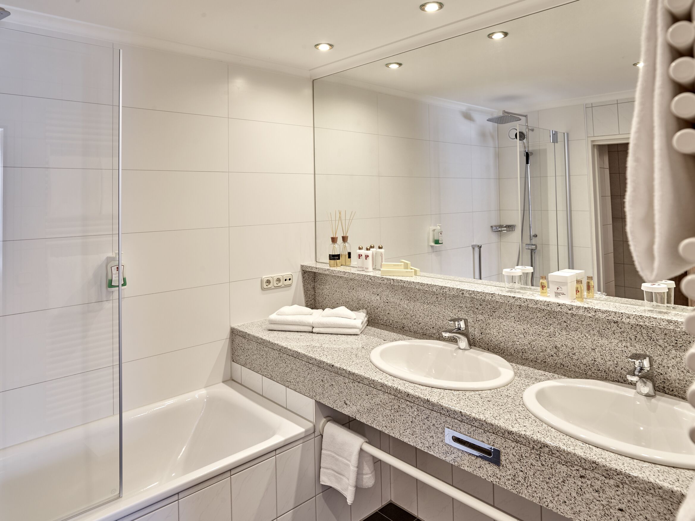 Une salle de bain moderne avec deux lavabos, une douche et un grand miroir.
