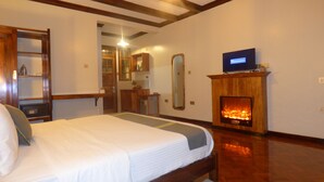 Une chambre à coucher avec un lit, une télévision, une cheminée et un plafond en bois.