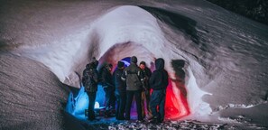 Un grupo de personas dentro de una estructura que se asemeja a una cueva, con paredes de hielo.
