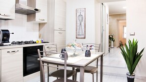 A modern kitchen with a dining area, featuring a gas stove, oven, and a dining table with chairs. - B&B Porta San Paolo (Campobasso)