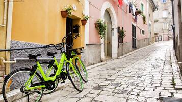 A narrow cobblestone street with a bright green bicycle parked against a yellow building.