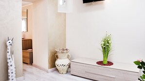A hallway with a white vase, a wooden cabinet, and a minimalist TV on the wall. - B&B Porta San Paolo (Campobasso)