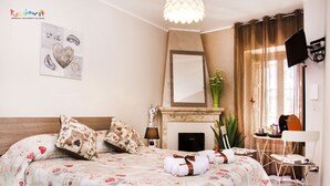 A bedroom with a bed, a fireplace, a mirror, a TV, and a small table with a chair. - B&B Porta San Paolo (Campobasso)