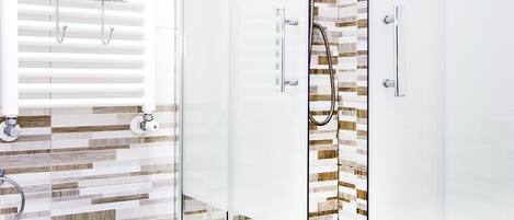 Un baño moderno con cabina de ducha de vidrio, zona de ducha con azulejos blancos y pared con estampado de madera.