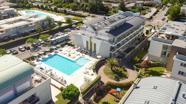 A modern hotel with a large swimming pool, multiple lounge areas, and a rooftop terrace. - Residenza Turistica Alberghiera Blue Marine (San Michele al Tagliamento)