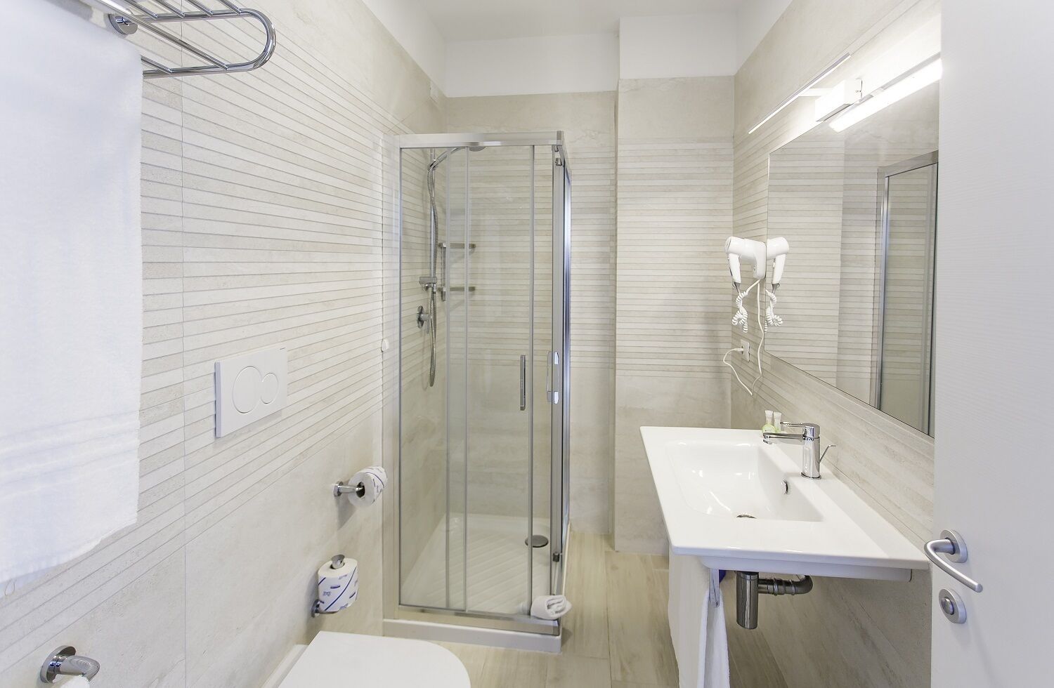 Ein modernes Badezimmer mit einer Duschkabine aus Glas, einem weißen Waschbecken und einer Toilette.