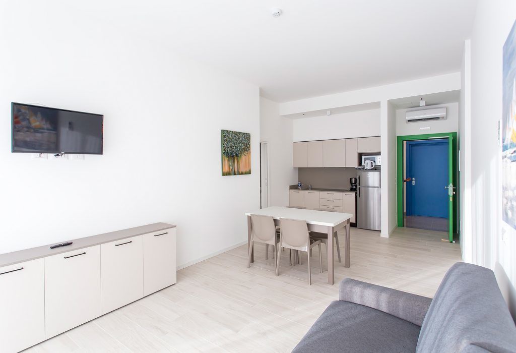 Un appartement moderne comprenant un salon, un coin repas, une kitchenette et un téléviseur fixé au mur.
