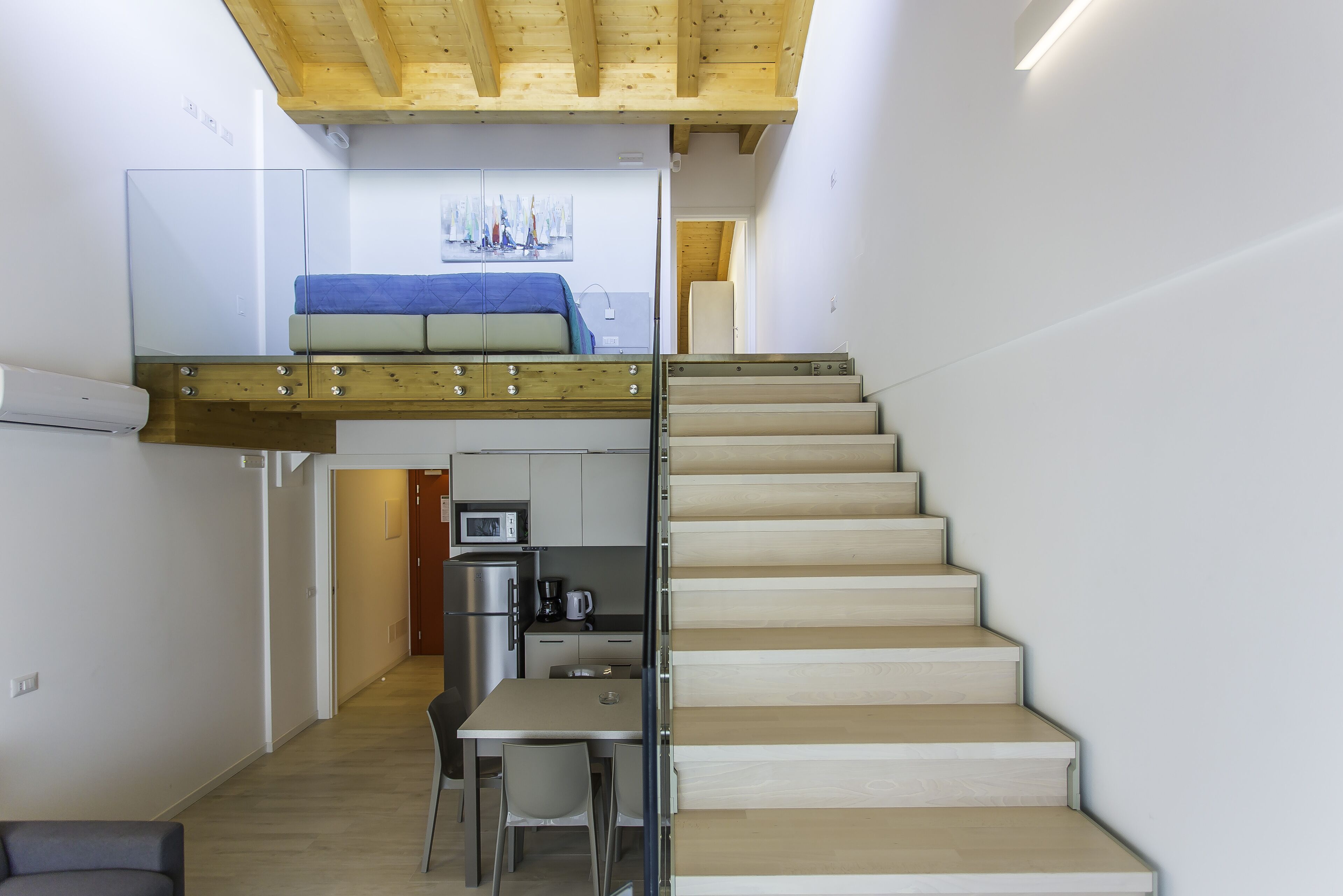 Un espacio habitable compacto con un dormitorio tipo altiloce, una zona de comedor y una cocina.