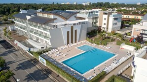 A modern hotel with a swimming pool, multiple balconies, and a parking area. - Residenza Turistica Alberghiera Blue Marine (San Michele al Tagliamento)