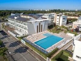 Un hotel moderno con piscina, diversi balconi e un'area parcheggio.