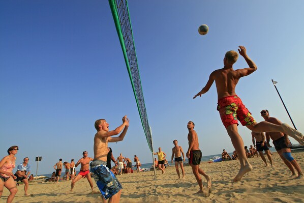 Partido de voleibol de playa con jugadores usando diversos trajes de baño.