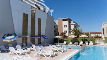 Una piscina al aire libre de temporada, sombrillas