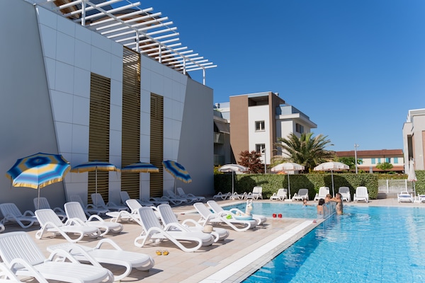 Una piscina al aire libre de temporada, sombrillas