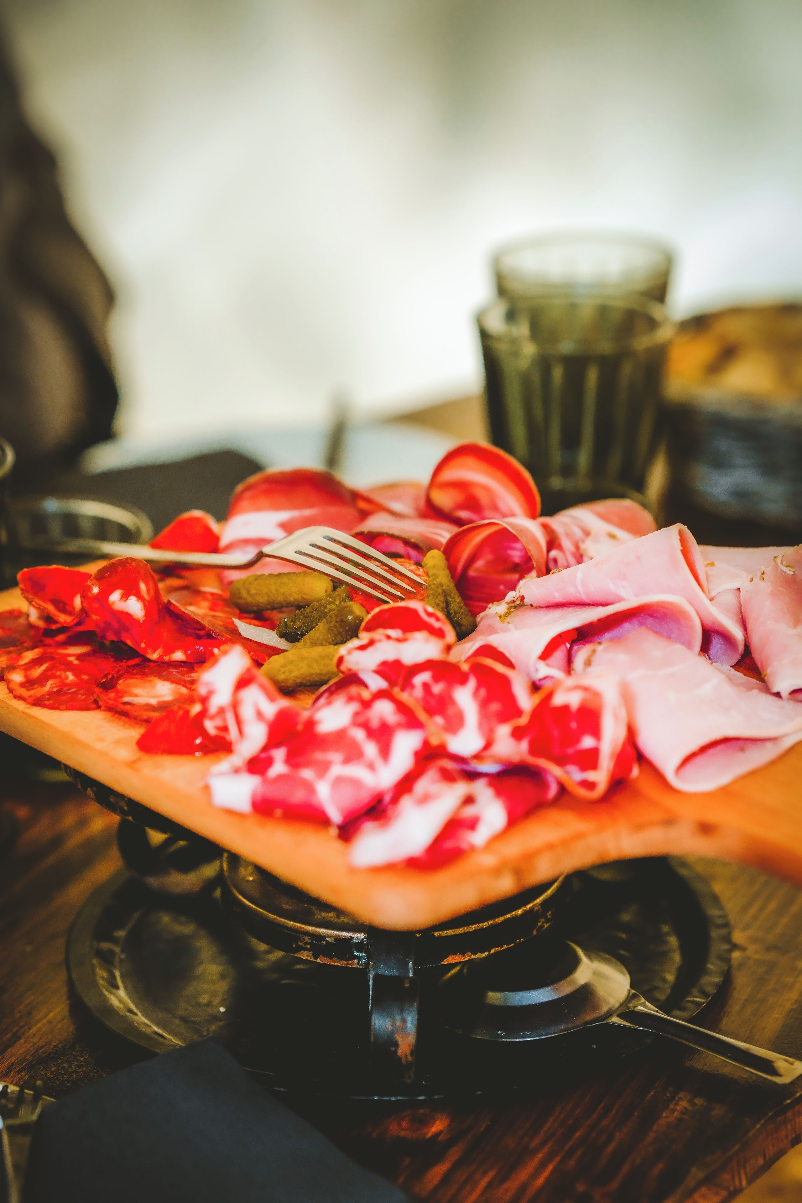 A wooden serving board with various meats and pickles.