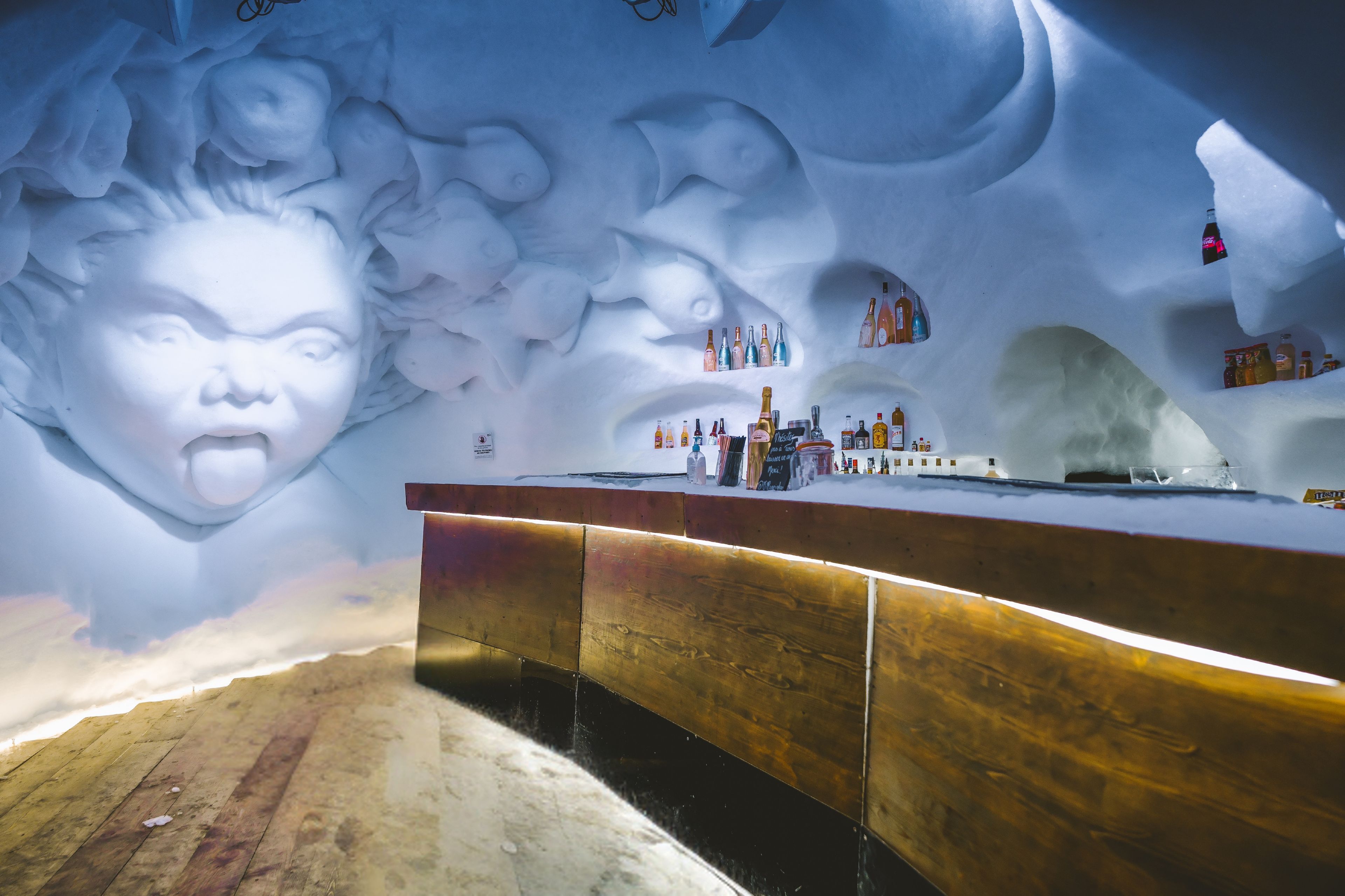 An ice bar with a wooden counter and shelves of bottles.