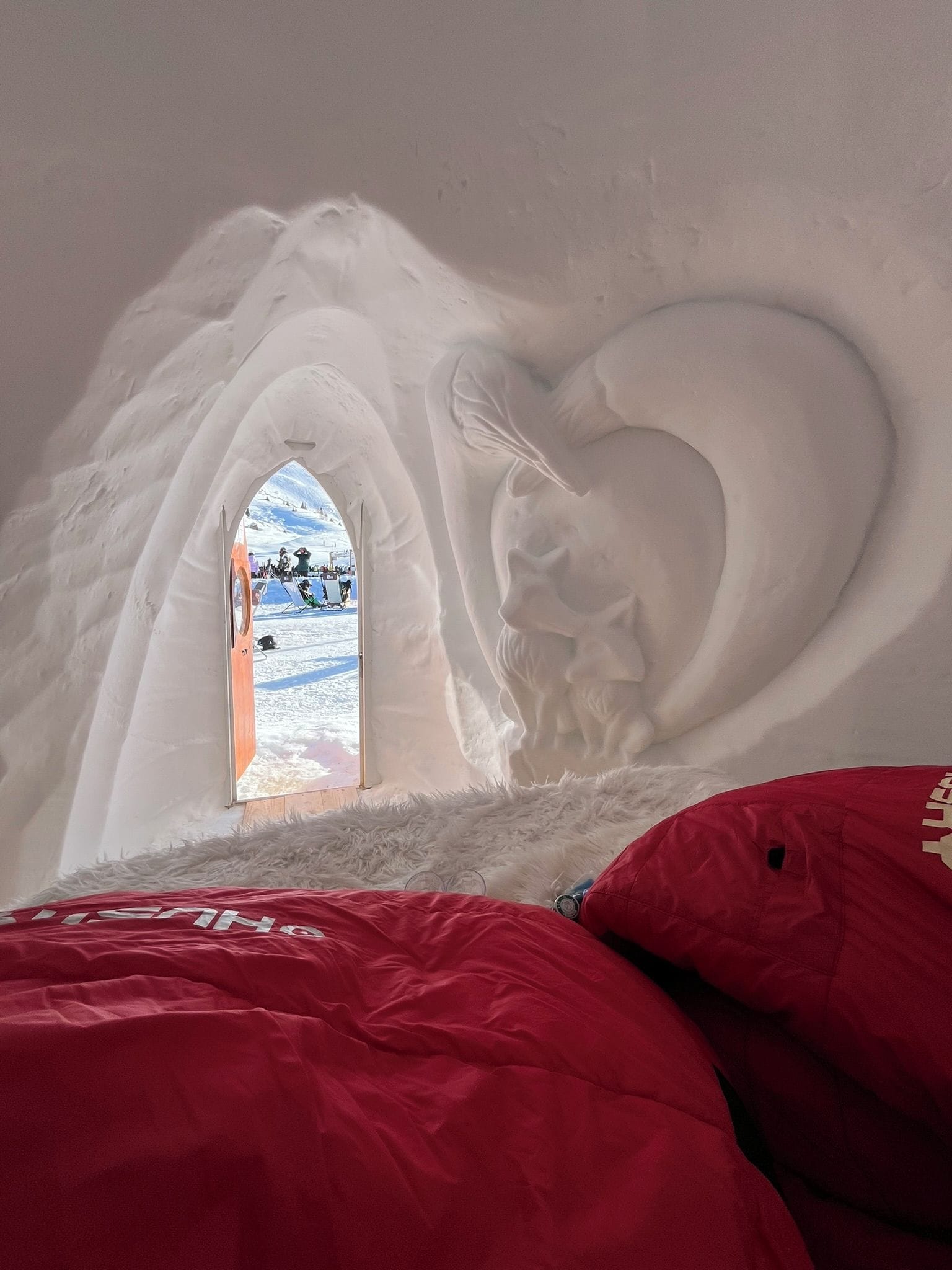 An igloo with a heart-shaped window and a view of a snowy landscape.