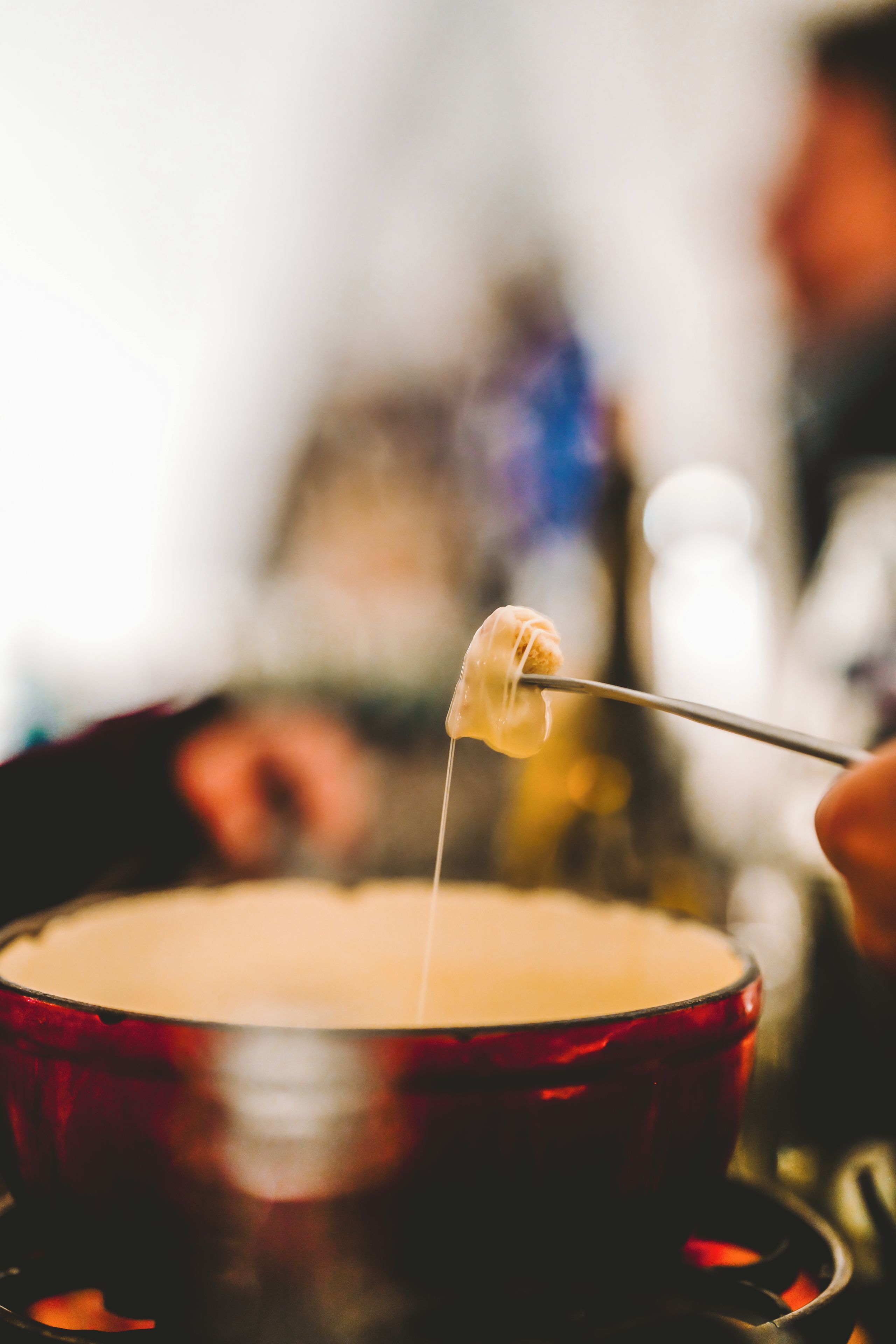 Gros plan d’un plat de dessert à la surface dorée et brune, qui pourrait être une fondue ou un chocolat chaud, avec une cuillère contenant un morceau de nourriture.