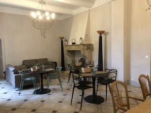 A living room with a fireplace, a sofa, and a dining area with chairs and a table.
