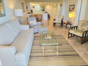 Relax in a comfortable living room with a sofa, coffee table, and dining area, surrounded by artwork.