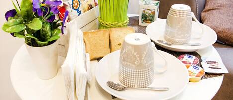 Un plateau de petit-déjeuner comprenant deux tasses, une assiette avec une cuillère et une petite plante en pot.