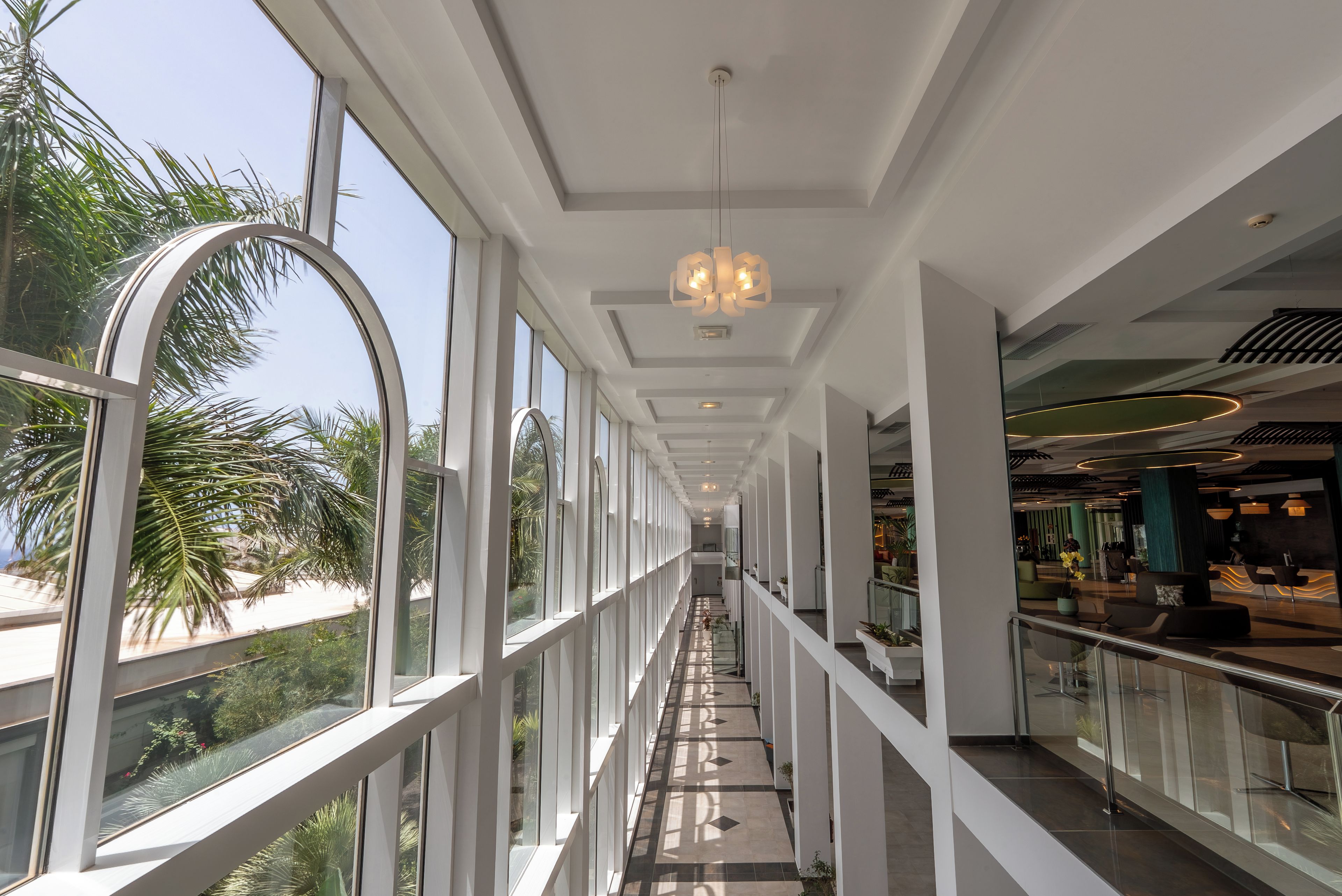 A modern interior with a glass balustrade, a central walkway, and a reception area.