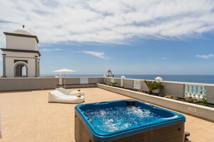 Una terrazza sul tetto con una vasca idromassaggio, poltrone relax e vista mare.