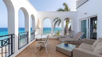 Un balcon avec vue sur la mer, aménagé avec une table, des chaises et un canapé.