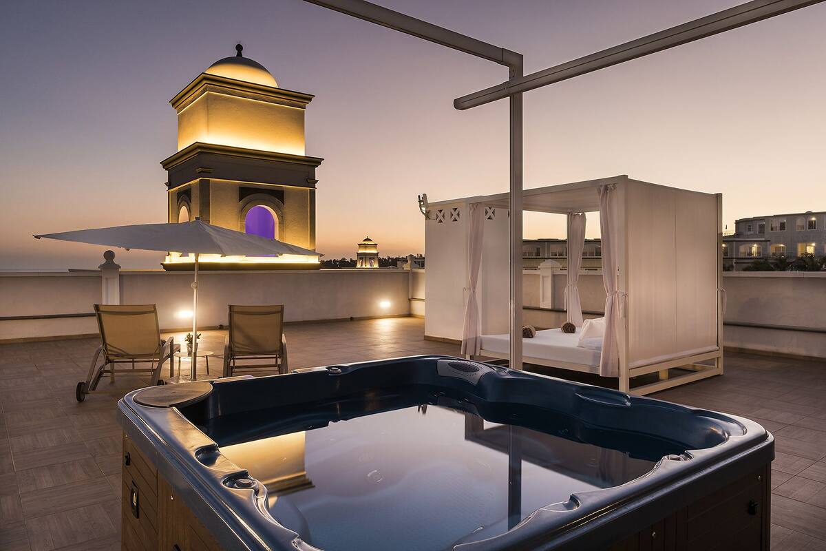 A rooftop with a hot tub, a canopy bed, and a view of a building with a dome.
