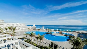 A resort pool area with a large pool, palm trees, and a view of the ocean. - Royal Palm Resort & Spa - Adults Only (Pajara)