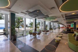 A spacious lobby with a modern design, featuring a mix of seating areas, a dining table, and large windows offering views of the outdoors. - Royal Palm Resort & Spa - Adults Only (Pajara)
