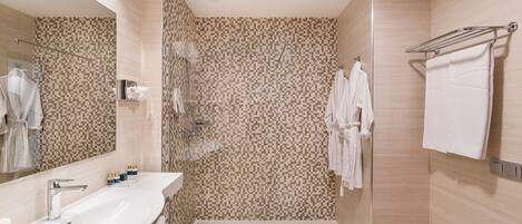 A modern bathroom with a large mirror, a sink, a shower, and a towel rack.
