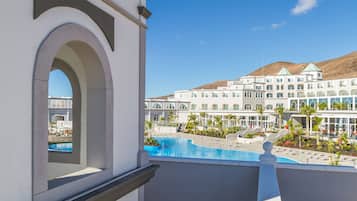 Un hotel con piscina, vista sulle montagne e un edificio alto con diversi piani.