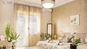 Un dormitorio bien iluminado con cama, mesita de noche y un amplio ventanal con cortinas.